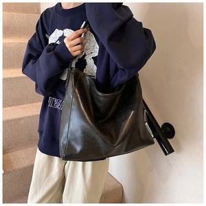 Detail of black large capacity faux leather hobo bag with textile strap on a model