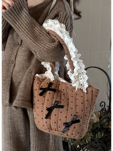 Dettaglio borsa shopper in cotone trapuntato marrone con fiocchi neri e bordo in pizzo