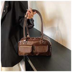 Detail of vintage brown glossy leather shoulder bag with dual front pockets and silver zipper