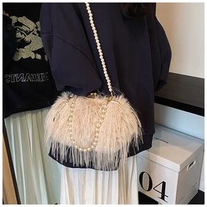 Detailed close-up of beige plush faux fur handbag with elegant pearl strap and bow detail