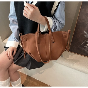 Detail of a brown geometric PU leather handbag with side drawstrings and smooth matte texture