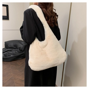 Détail du sac à épaule en fausse fourrure crème porté par un mannequin en intérieur