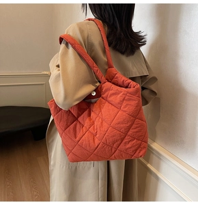 Detail of orange quilted tote bag featuring diamond stitch texture on shoulder bag
