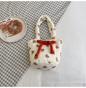 Detail of quilted cotton bucket bag with brown bear patterns and orange rope bow accent