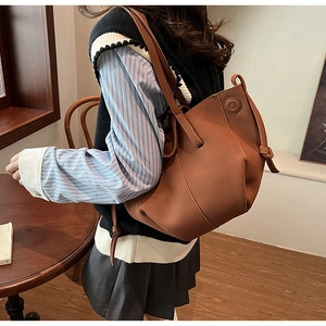 Detailed side view of brown pleated faux suede tote bag with decorative knot detail