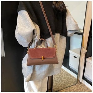 Detail view of contrast color PU crossbody bag with gold handle and dark red flap