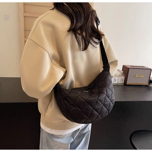 Quilted nylon half-moon shoulder bag in black worn by a model in a cozy interior setting