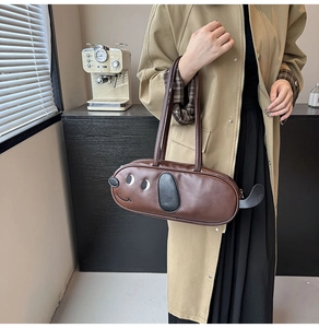 Vue détaillée du sac à bandoulière en similicuir marron en forme de chiot porté par un mannequin