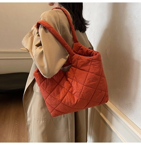 Detail view of large quilted tote bag in orange-red fabric with soft diamond texture