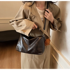 Detail of dark brown PU leather shoulder bag with cute plush bear pendant accessory