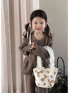 Dettaglio borsa trapuntata beige con stampe di orsi e pizzo indossata da un bambino