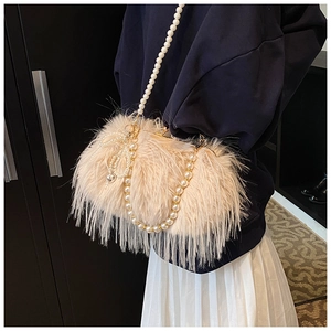 Detail of plush faux fur shoulder bag with pearl chains and bow charm in apricot