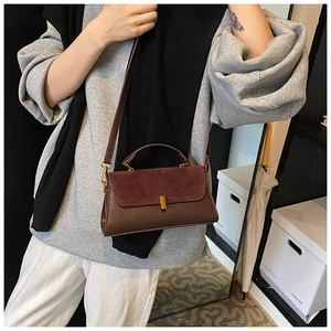 Close-up of contrast faux leather and suede shoulder bag with gold metal clasp detail