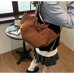 Brown faux leather tote bag with decorative side knots worn in a cafe setting