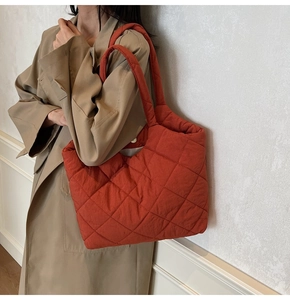 Detail of red quilted nylon shoulder bag showing puffy texture and magnetic closure