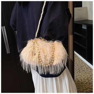 Detail of plush beige crossbody bag featuring heart charm and pearl shoulder straps