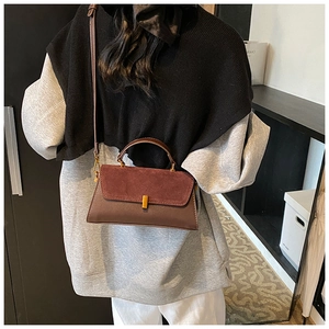 Detail view of a stylish two-tone burgundy and brown PU leather crossbody bag on a model