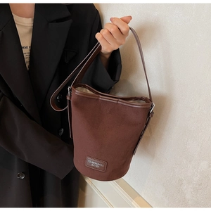 Detailed close-up of dark brown bucket bag with smooth leather edges and premium brand label