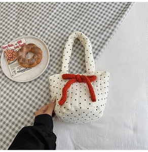 Close-up of quilted cotton tote bag with black polka dots and a red knitted bow accent
