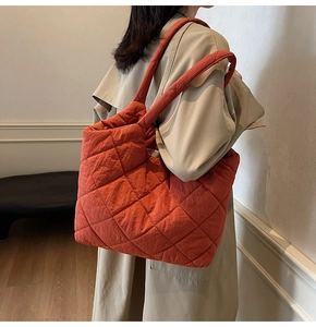 Close-up of brick red quilted tote bag featuring classic diamond stitching and nylon texture