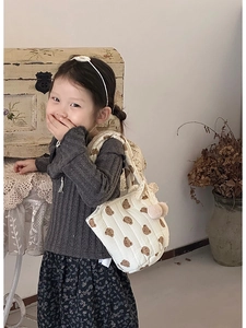 Gros plan détaillé d'un sac cabas en coton matelassé avec motifs d'ours et pompons doux