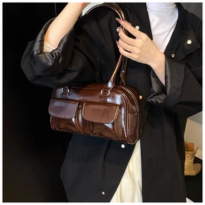Detail of a shiny dark brown PU leather shoulder bag with utility flap pockets on a model