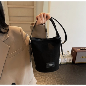 Detail of minimalist black PU bucket bag with brand logo and retro lifestyle props
