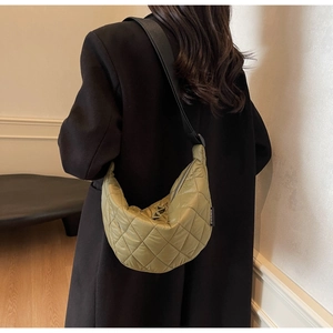 Detail of olive green quilted half-moon shoulder bag with classic diamond stitching