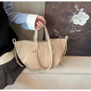 Detail of elegant beige faux leather tote bag with reinforced handles and side drawstring accent