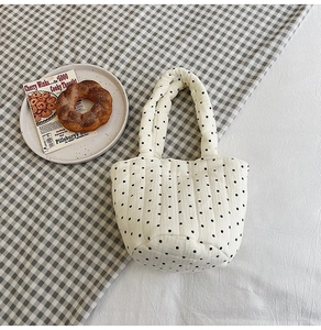 Close-up of white quilted tote bag with black polka dots on a cozy checkered fabric