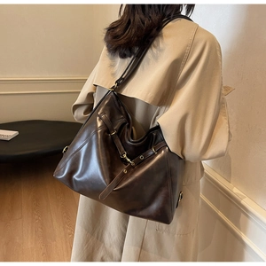 Detailed close-up of dark brown PU leather tote bag with soft texture and golden buckles