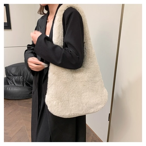 Chic sac à épaule en fausse fourrure crème porté par un mannequin en décor minimaliste