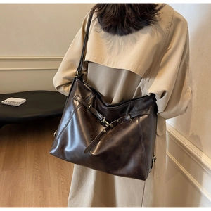 Detail of a large brown PU leather tote bag featuring golden buckles and a vintage texture
