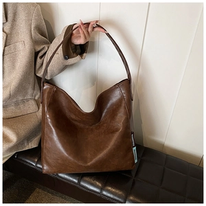 Detail of vintage brown PU leather tote bag with MUDUOSTUDIO woven label and retro matte finish