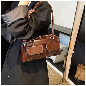 Detail view of glossy brown PU leather shoulder bag with decorative front flap pockets