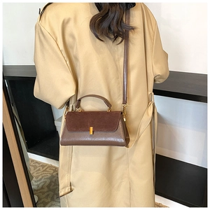 Detailed view of a brown contrast faux leather handbag worn with a trench coat