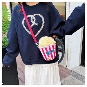 Detail shot of creative popcorn-shaped crossbody bag with soft pink striped textures