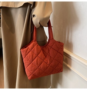 Detail of red-brown quilted tote bag showing matte fabric texture and stitching