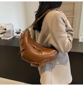 Vue détaillée du sac cabas marron en demi-lune avec nœuds en cuir et large bandoulière