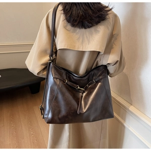 Detail of a vintage dark brown PU leather tote with stylish metal belt buckle on back