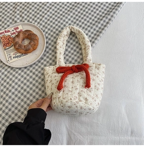 Close-up of quilted floral cotton bag with a large red knit bow and a sturdy top handle