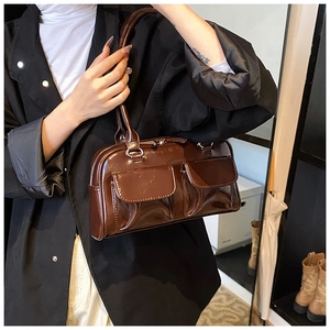 Detail of a dark brown glossy PU leather shoulder bag with symmetric flap pockets