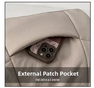 Detail showing the external pocket of a beige quilted dumpling bag with a smartphone inside