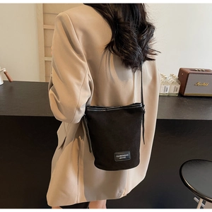 Modern black PU leather bucket bag worn by model in a minimalist coffee shop setting