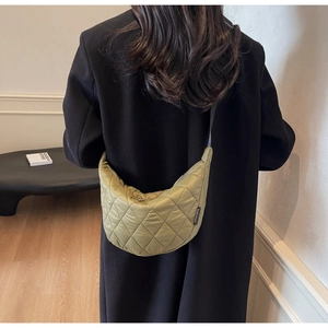 Detail of olive green quilted crescent bag showing fabric texture and crossbody strap