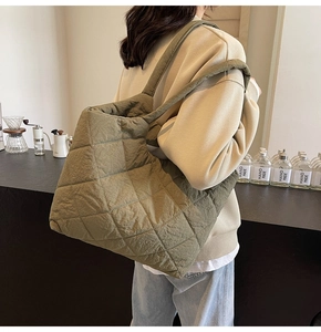 Detail of olive green quilted shoulder bag with wide strap in a cozy coffee shop setting
