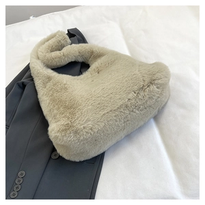 Détail de la texture d'un sac à bandoulière en fausse fourrure beige sur blazer