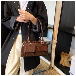Detail showing glossy brown PU leather texture and silver metal rings on a shoulder bag