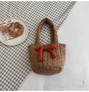 Detailed macro of brown polka dot quilted cotton handbag with a bright orange knit bow