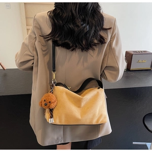 Detailed view of yellow PU leather shoulder bag with cute brown dog plush charm pendant